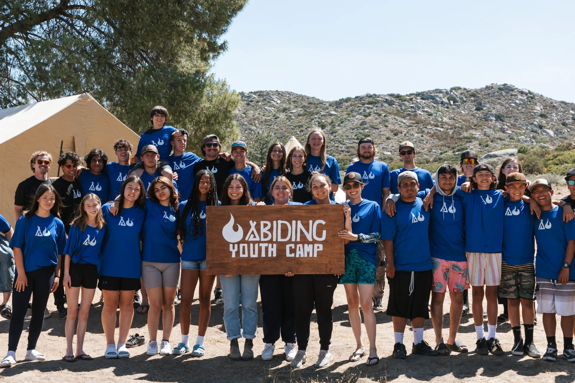 Abiding Youth Camp group gathered around the camp sign