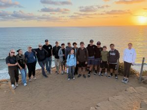 Abiding Place Youth Ministry group gathered above the ocean at sunset