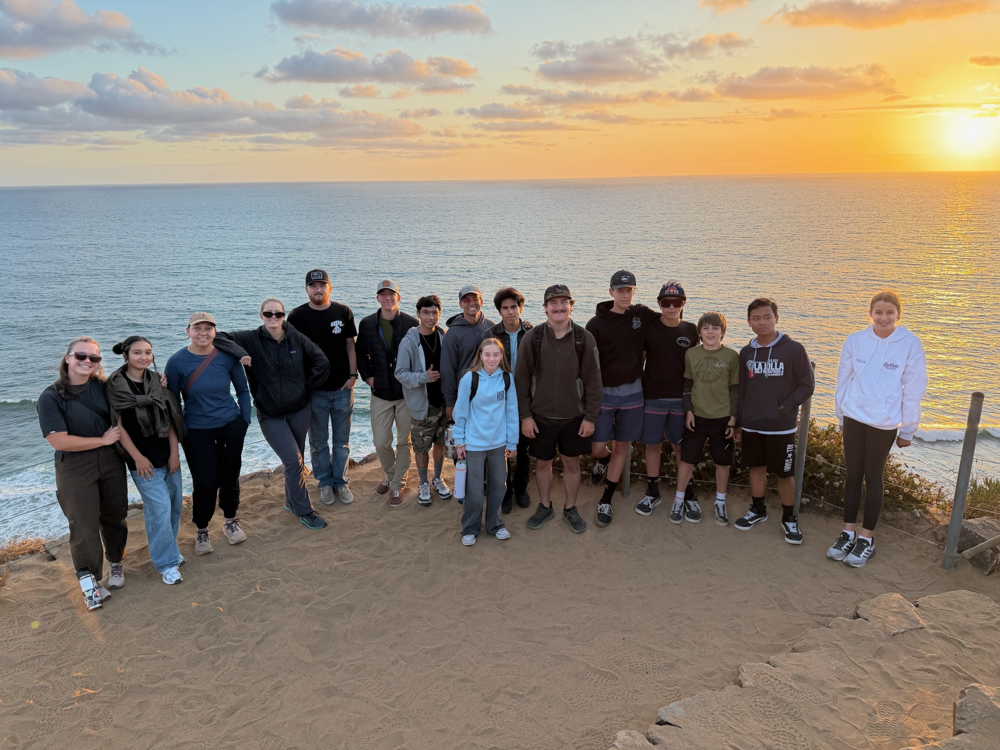 Abiding Place Youth Ministry group gathered above the ocean at sunset
